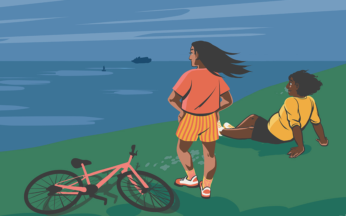 Two people enjoying looking out over the ocean after riding their bikes up a hillside.